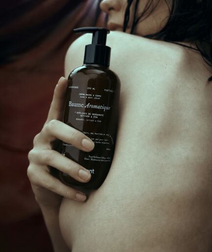 Personne à la peau d’apparence hydratée tenant un flacon de crème hydratante naturelle mains & corps Motsent