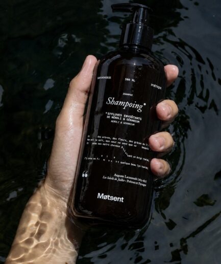 Main tenant un flacon de shampoing naturel parfumé Motsent 500 ml au néroli et géranium