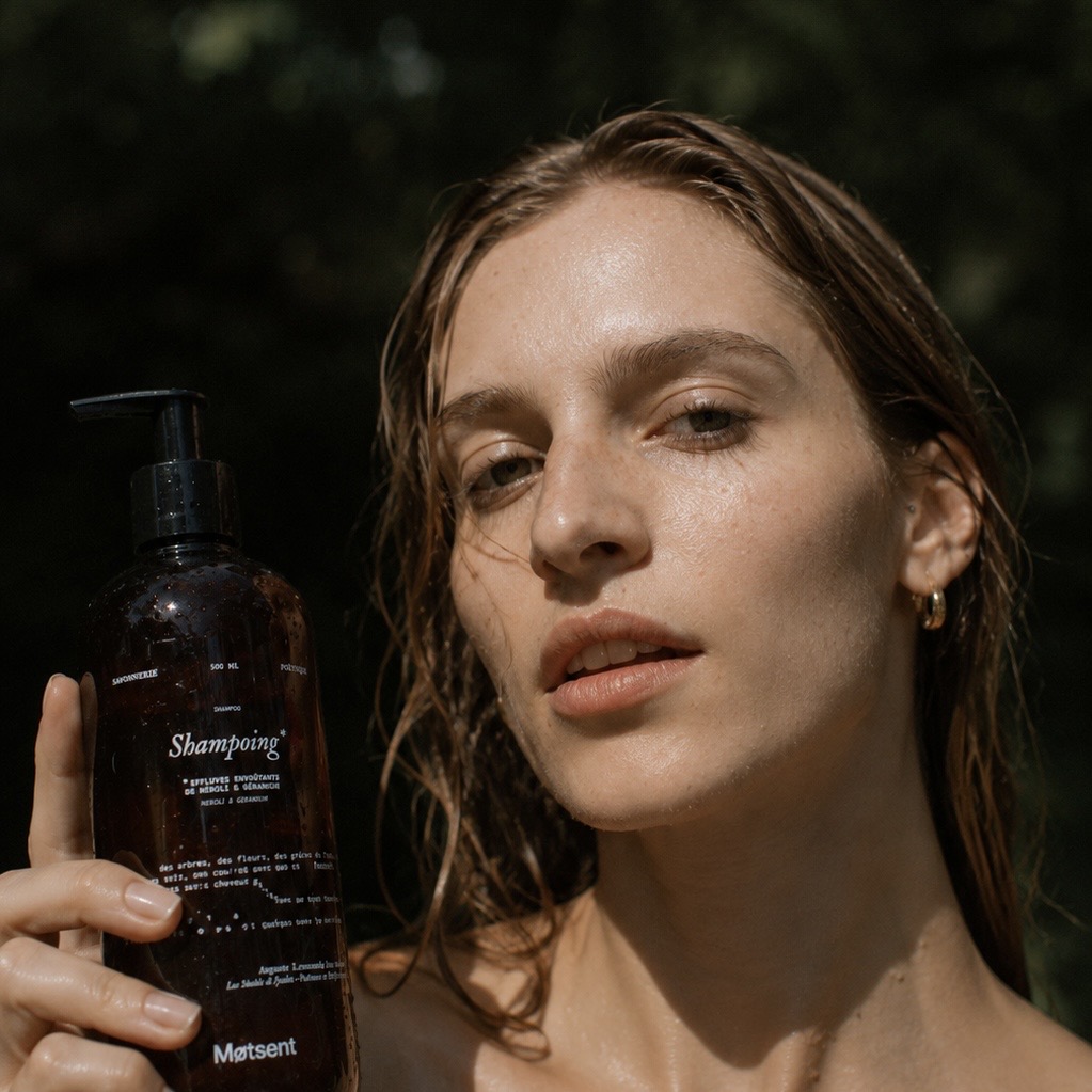 Femme aux cheveux mouillés tenant le shampoing Motsent pour tous types de cheveux